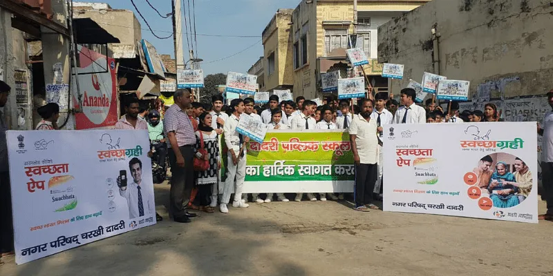स्वच्छता को बढ़ावा देने के लिए सड़क रैली में भाग लेते हुए स्थानीय निवासी और छात्र
