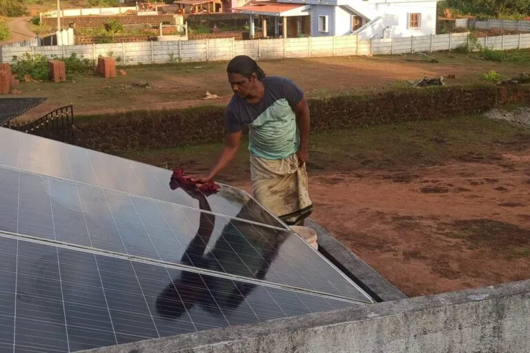 कर्नाटक के अलूर में अपने सौर पैनल को साफ करते हुए कुम्हार रघुराम कुलाल। तस्वीर- प्रणव कुमार