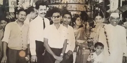 Founder Suresh Shah (seen behind the man with glasses). Behind them is the paan shop from where Sapna Book House started.