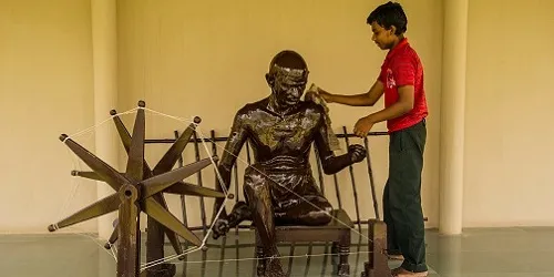 A man cleans a statue of Gandhi sitting at a spinning wheel. (Getty Images)