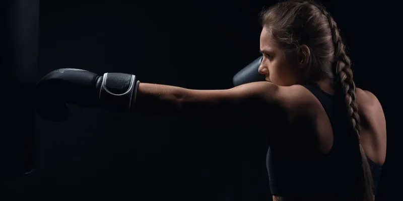 young girl in boxing gloves pushes the bag