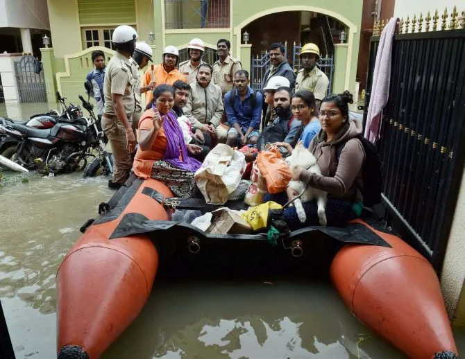 Bengaluru : Karnataka Fire & Emergency service personnel rescue the families on boat from flood-hit Kodichikkanhalli area following incessant rains in Bengaluru on Friday. PTI Photo by Shailendra Bhojak (PTI7_29_2016_000164B)
