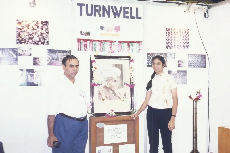 Anima at a stall at an industrial expo representing Turnwell. It is the small-scale industry manufacturing automative parts, founded by her parents. 