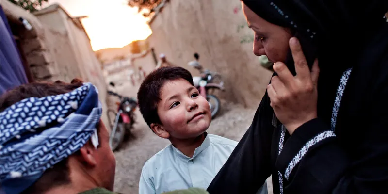 A polite young men is looking to her Mother while she is talking on phone