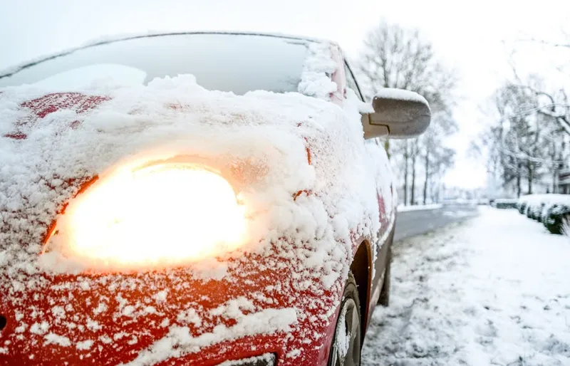 Snow-covered red sedan