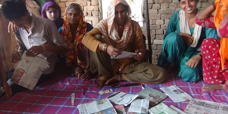 अपने बनाए लिफाफों के साथ बच्चों की मांएं